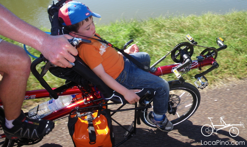 A child who is sleeping at the front of a Hase Pino semi recumbent tandem bike during the Tour de Bourgogne tour on a bicycle