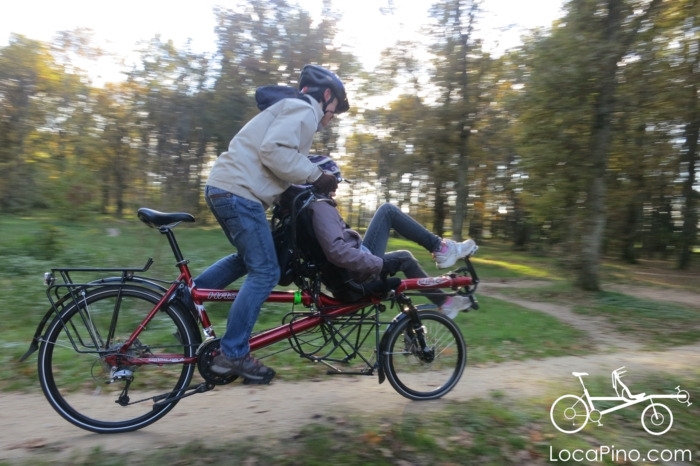 Two children playing with a Hase Pino tandem bike in a forest